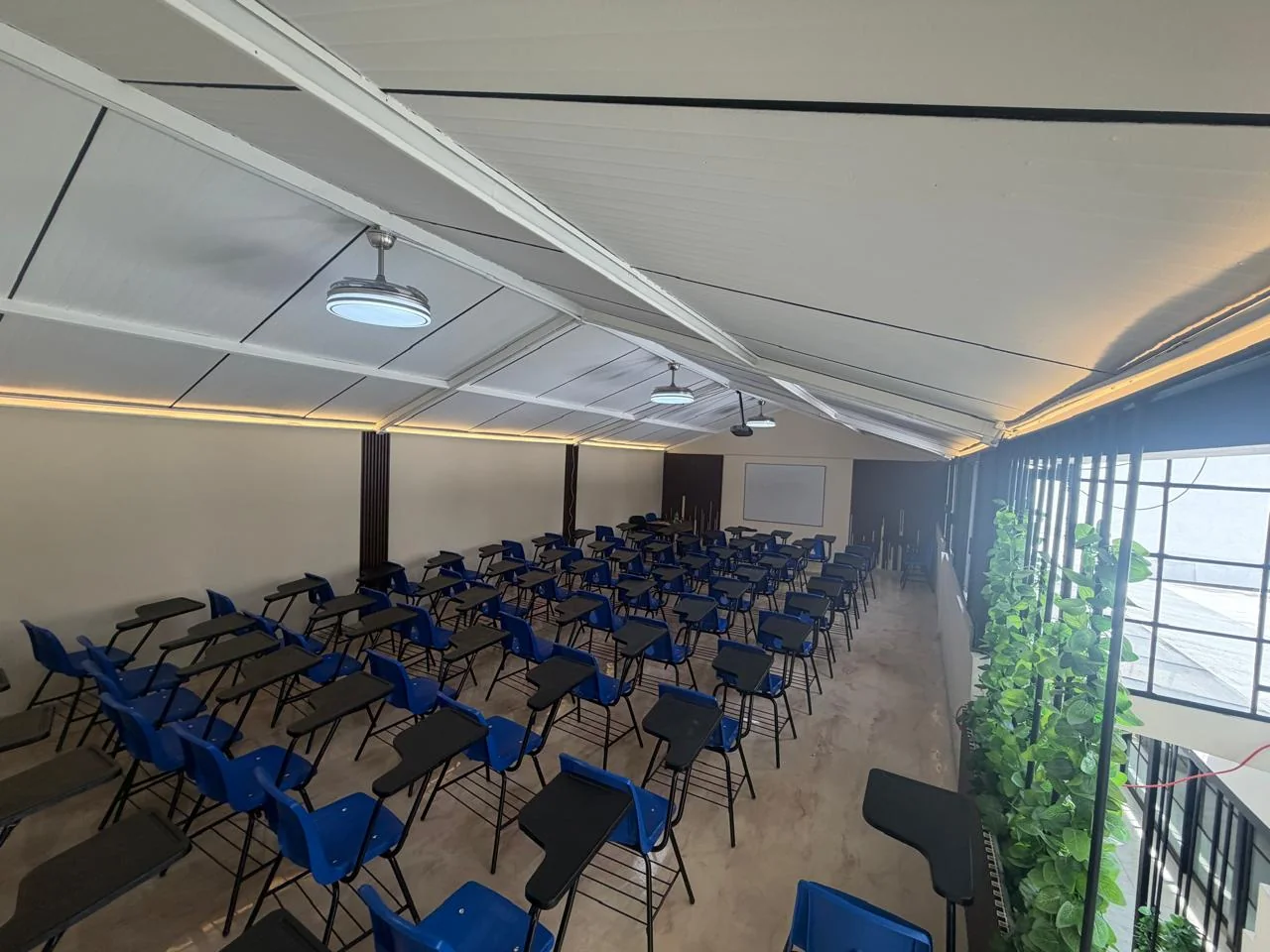 Salón de clases con butacas, pizarrón y proyector